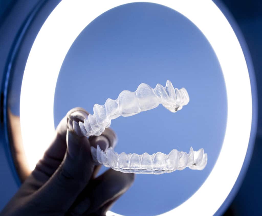 Close-up of clear aligners in front of a ring light, showcasing their transparent design and portability for orthodontic treatment.